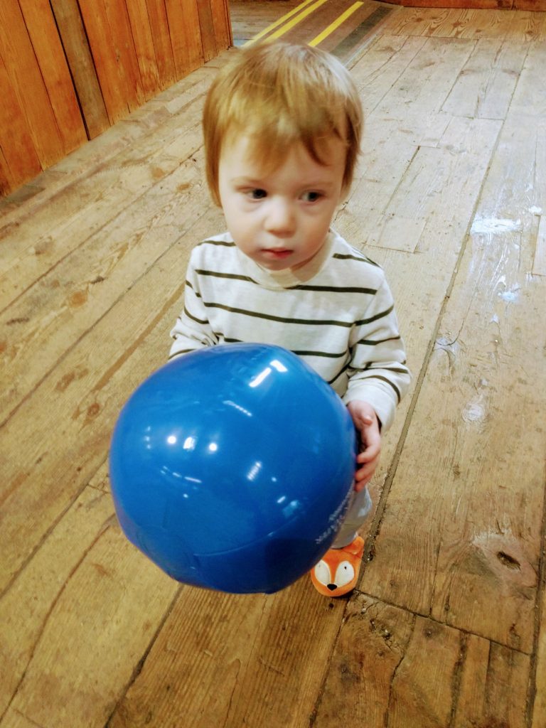 autistic toddler holding ball and looking unsure
