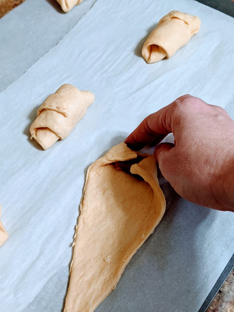 rolling up the soft caramel in crescent roll dough for fall dessert