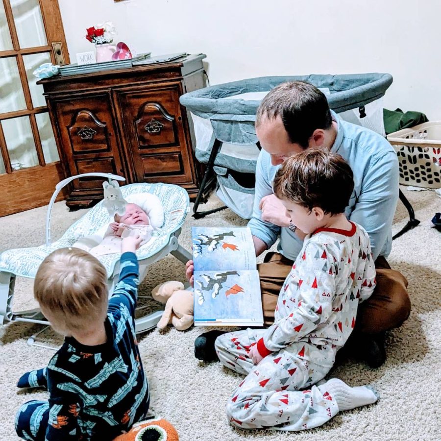 Family reading time with newborn, preschooler and toddler in the fourth trimester