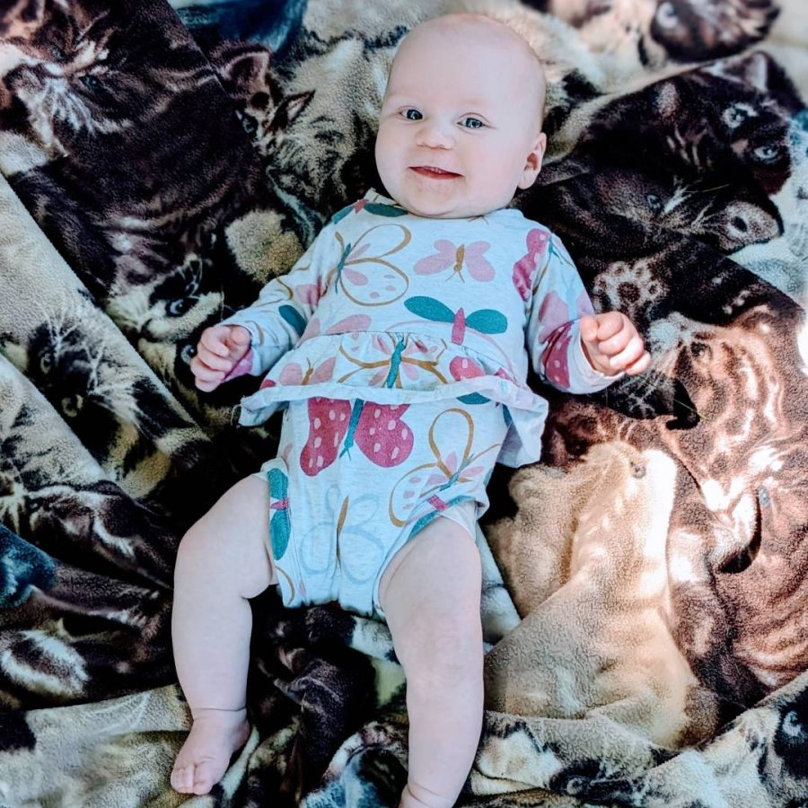 four month old smiling infant outside on blanket